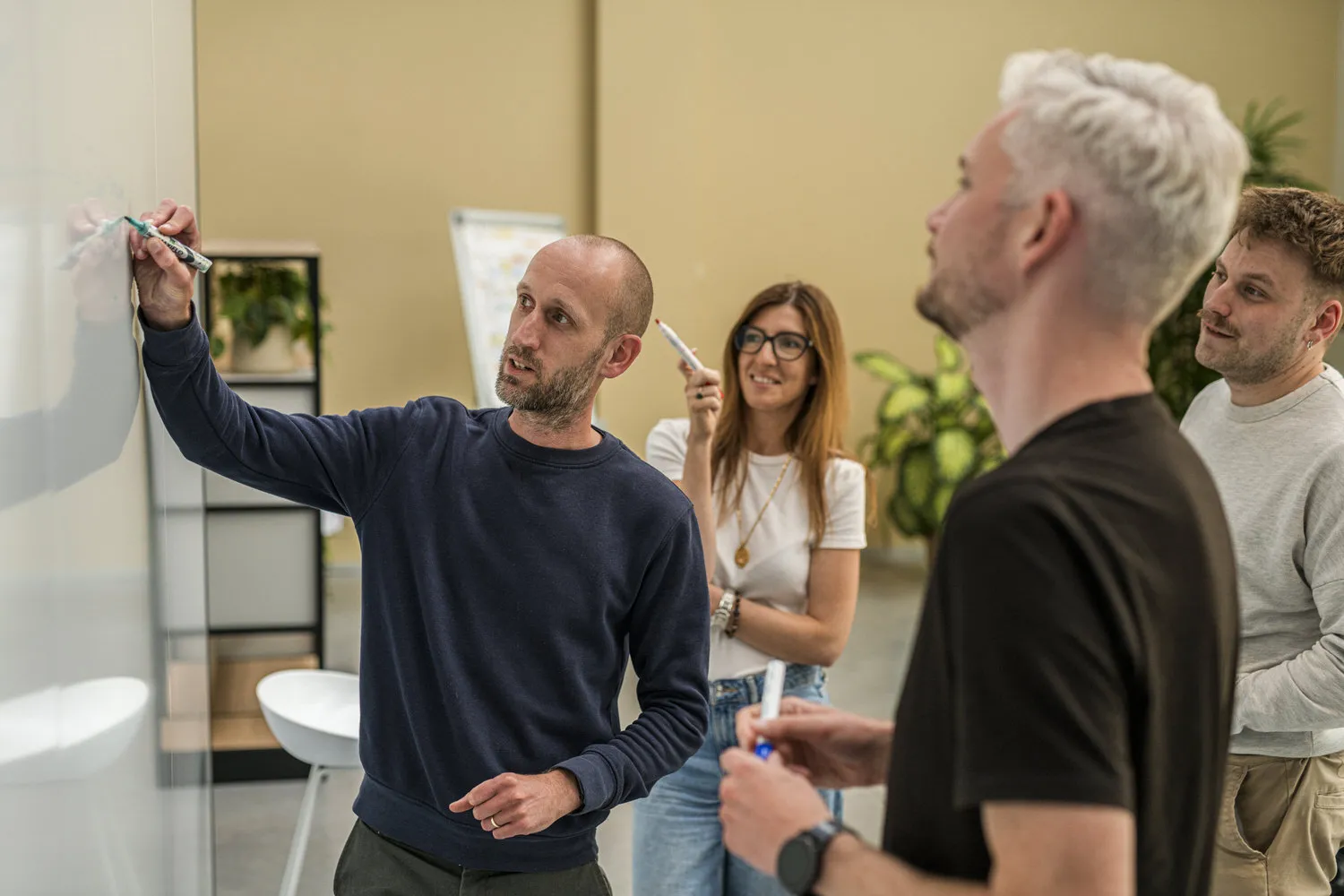 Vier collega's werken een idee uit aan een whiteboard